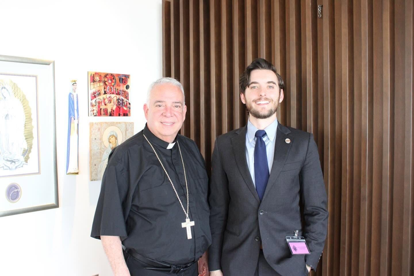 Joe Picozzi standing with a priest during a parish visit