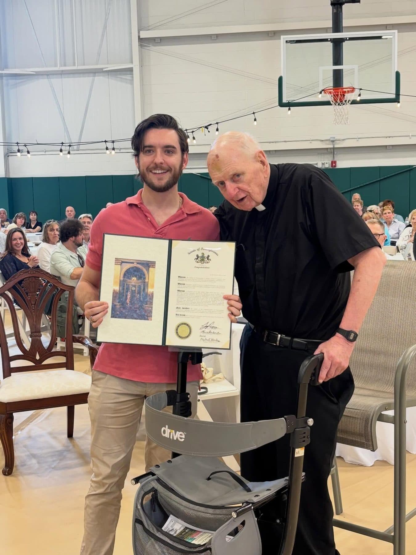 Joe Picozzi presenting a Senate citation to a priest in a parish gym