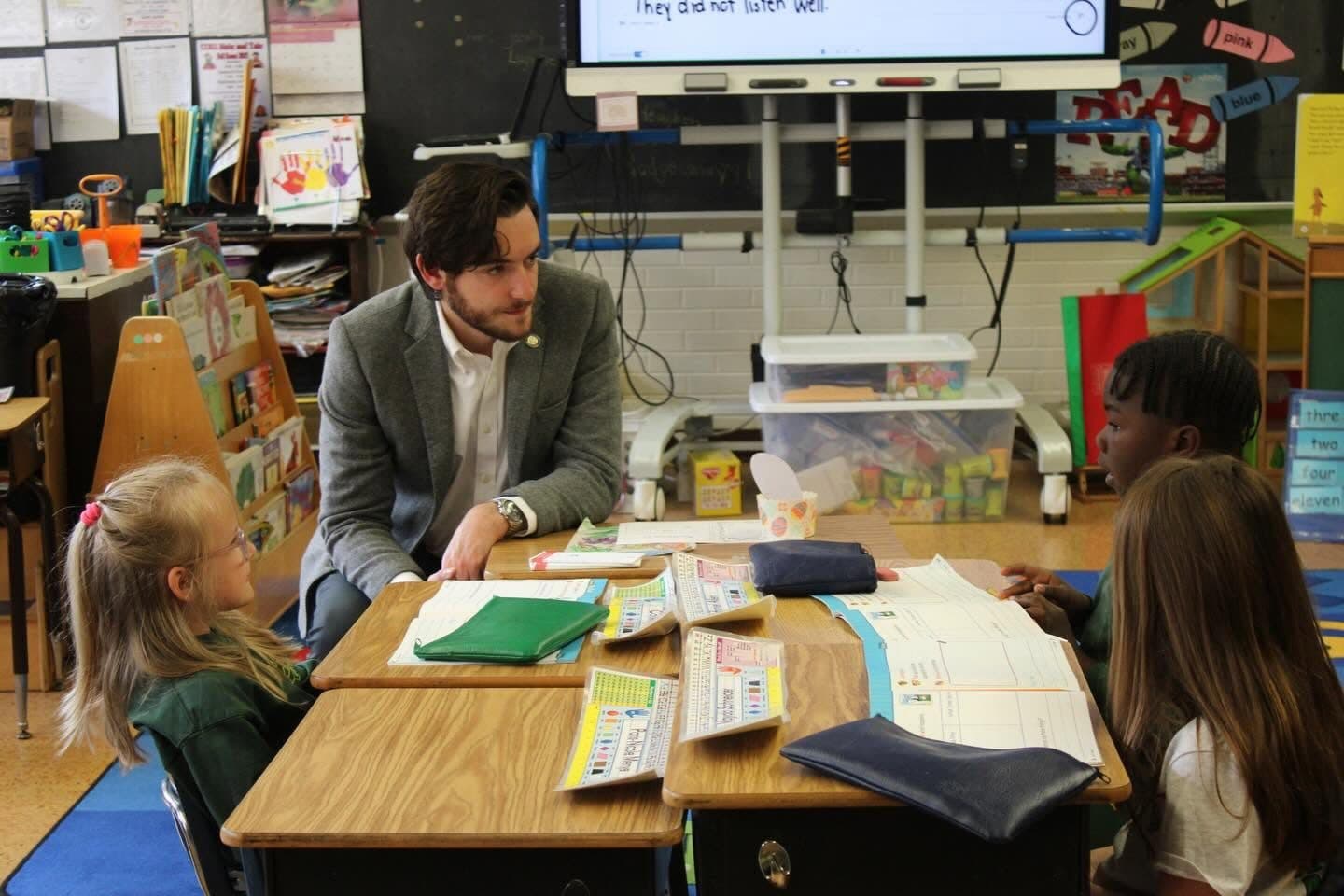 Joe Picozzi talking with elementary school students at their desks