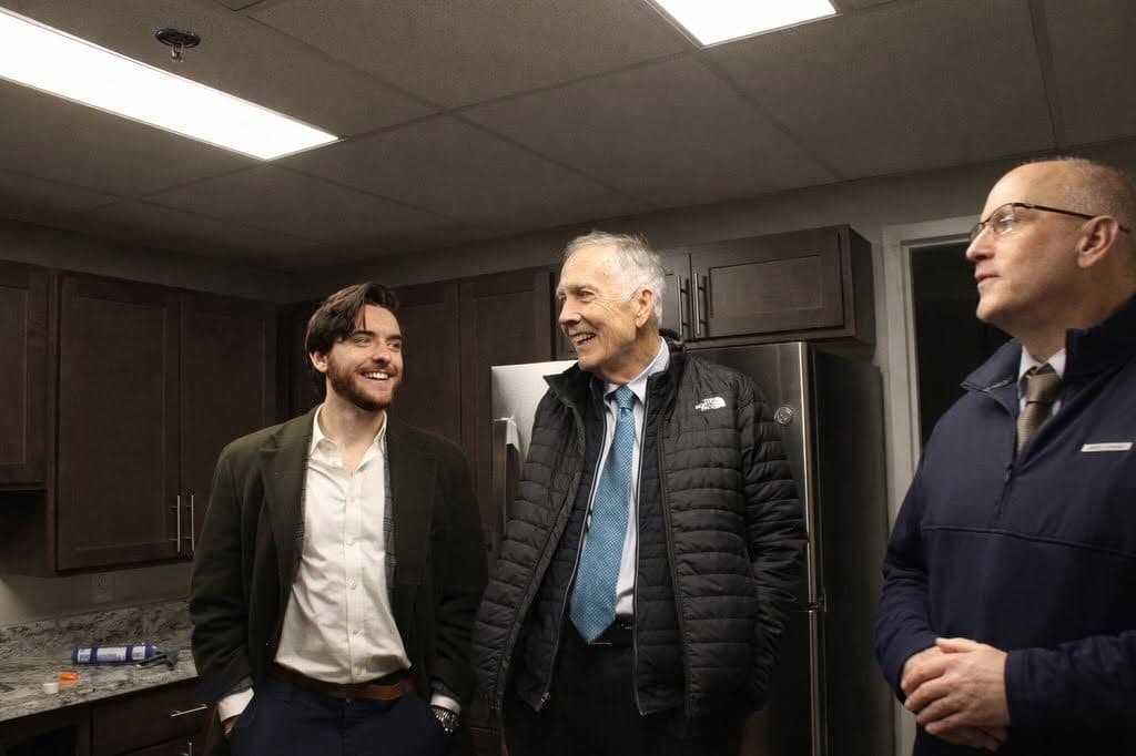 Joe Picozzi laughing with two men in a kitchen